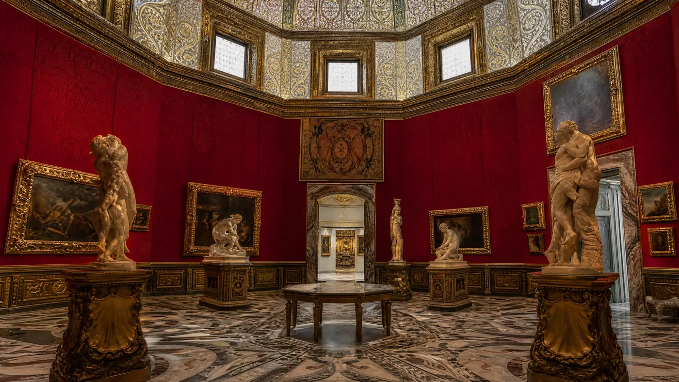 Una sala ottagonale rossa con statue di marmo e dipinti appesi alle pareti